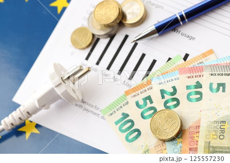 European union Euro money bills and coins with european electricity utility bill on table European union Euro money bills and coins with european electricity utility bill on table 125557230