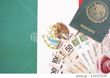 Mexican pesos money bills in big amount and passport lies on Mexico flag close up Mexican pesos money bills in big amount and passport lies on Mexico flag close up 125557247