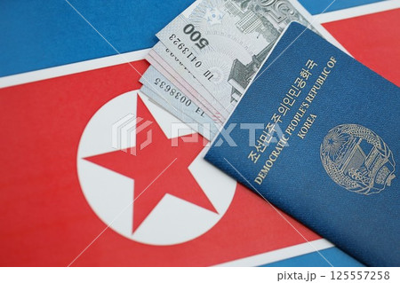 North Korean won money bills in big amount and passport lies on People Republic of Korea flag North Korean won money bills in big amount and passport lies on People Republic of Korea flag 125557258