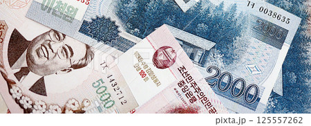 North Korean won money bills in big amount lies on white color table close up North Korean won money bills in big amount lies on white color table close up 125557262