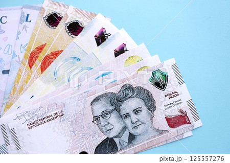 Argentine pesos money bills in big amount lies on teal color table close up 125557276
