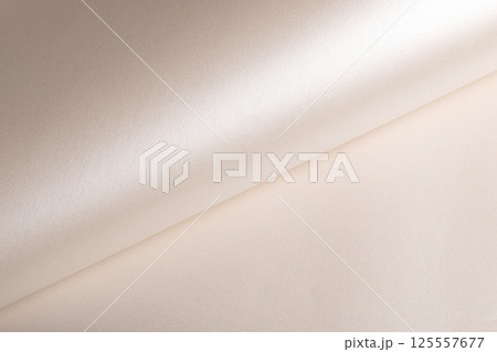 Background with satin paper texture. Rolled surface with glossy pearlescent finish, champagne and 125557677