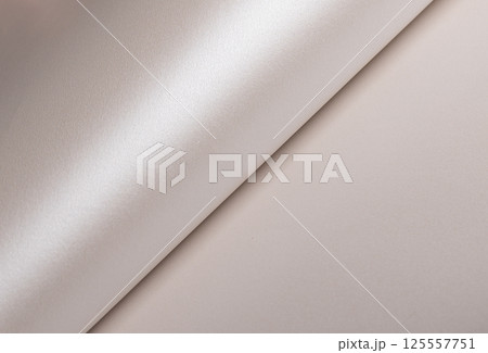 Paper background with satin pearlescent texture. Glossy curled folds, smooth surface in champagne 125557751