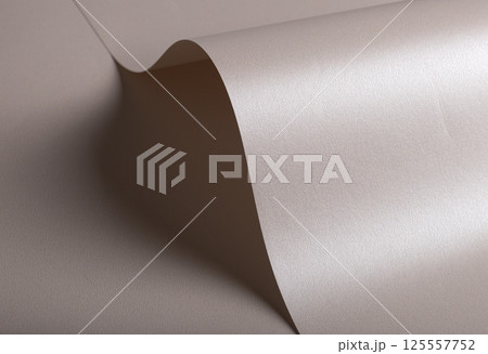 Paper background with satin pearlescent texture. Glossy curved folds, smooth sculptural surface in 125557752