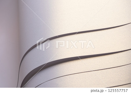 Paper background with satin pearlescent texture. Glossy folded wavy strips, layered surface in pale 125557757