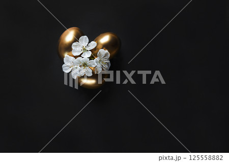 Golden Eggs with White Blossoms on a Black Background Symbolizing Elegance 125558882