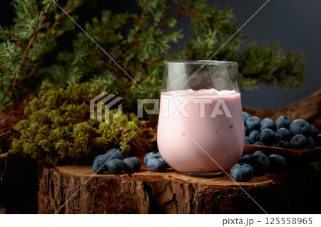 Blueberry smoothie in glass and fresh berries on a pine stump. 125558965