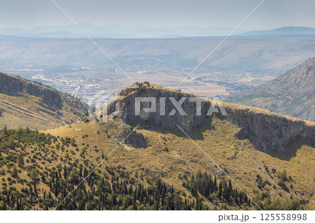 Landscape view from the Fortica hill, Bosnia and Herzegovina, Europe. Scenic view of a rugged mountain landscape with a distant town, showcasing nature's grandeur and serene beauty in the panorama. Landscape view from the Fortica hill, Bosnia and Herzegovina, Europe. Scenic view of a rugged mountain landscape with a distant town, showcasing nature's grandeur and serene beauty in the panorama. 125558998