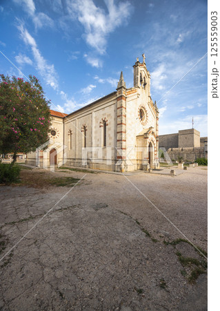 Ston, historic town in Peljesac peninsula in Croatia, Europe. Picturesque chapel with stone facade and bell tower stands serenely against a backdrop of blue sky and gentle clouds. 125559003