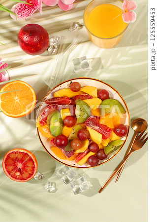Healthy breakfast with ingredients, kitchen background. Fruit salad with kiwi, mango, grapes, nuts, citrus fruits with chia seeds for weight loss and a glass of orange juice. Natural nutrition and 125559453