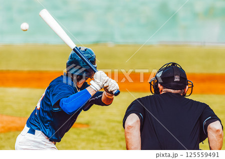 Baseball action, baseball player with bat waiting for ball with umpire, rear view. Team sports Baseball action, baseball player with bat waiting for ball with umpire, rear view. Team sports 125559491
