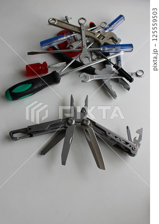 Folding utility knife with blades spread out against a pile of unnecessary tools vertical stock photo Folding utility knife with blades spread out against a pile of unnecessary tools vertical stock photo 125559503