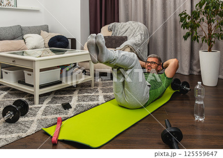 Man exercising at home on a green workout mat Man exercising at home on a green workout mat 125559647