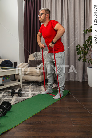Man using resistance bands for indoor workout session 125559679