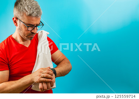 Man checking watch while adjusting towel on shoulder 125559714