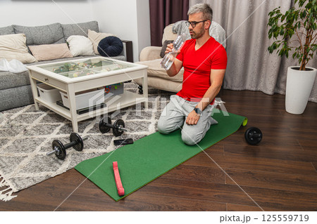 Man exercising at home with weights and water bottle Man exercising at home with weights and water bottle 125559719