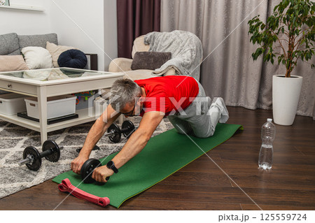 Man training with ab roller in living room Man training with ab roller in living room 125559724