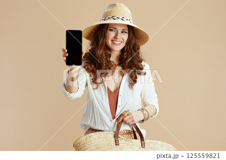 happy woman showing smartphone blank screen on beige happy woman showing smartphone blank screen on beige 125559821