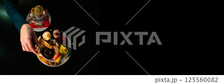 Elegant Female Hand Picking Pastry from Tray on Black Background - Isolated with Copy Space horizontal 125560082