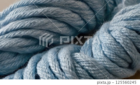 Pastel blue yarn gracefully coiling diagonally, revealing delicate texture and serene color against minimalist neutral background with elegant, soft styling 125560245