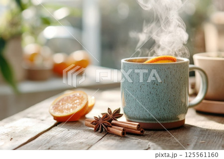 Warm mulled wine served in a cozy mug with spices and orange slices on wooden table 125561160