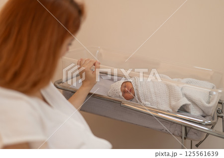 A young mother admires her newborn son in the maternity hospital. A young mother admires her newborn son in the maternity hospital. 125561639
