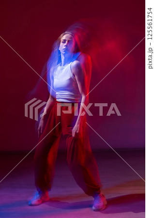 A young woman dances contemporary dances in blue and red light. Long exposure. Vertical photo. A young woman dances contemporary dances in blue and red light. Long exposure. Vertical photo. 125561754