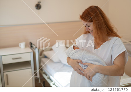 Caucasian woman holding newborn son in maternity hospital ward. Caucasian woman holding newborn son in maternity hospital ward. 125561770