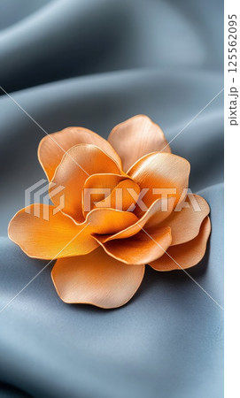Stylized gold flower brooch with matte and glossy textures on velvet fabric 125562095