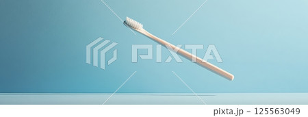 Single beige toothbrush floating on light blue background, promoting oral hygiene and dental care in a minimalist and visually appealing way 125563049