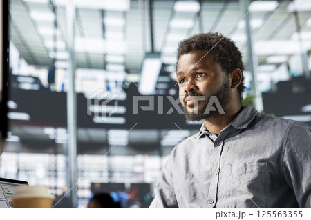 African american male professional works at desk in a corporation, working on financial planning and business strategy. Analyst focuses on company growth and effective resource allocation. 125563355