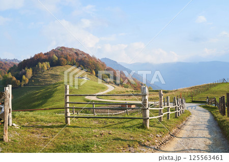 Picturesque Alps autumn landscape, wooden fence and mountain hills in Lombardy, Italy. 125563461