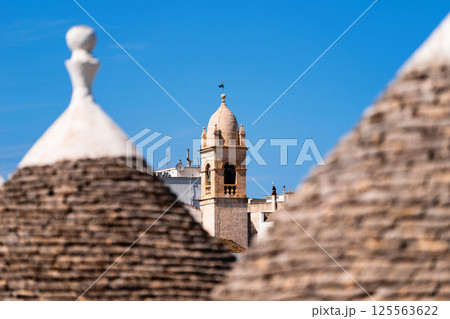 Trulli rooftops with bell tower in the background Trulli rooftops with bell tower in the background 125563622