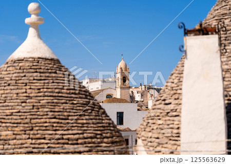 Trulli rooftops with bell tower in the background Trulli rooftops with bell tower in the background 125563629