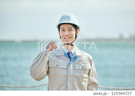 ガッツポーズをする作業着姿の20代の若い男性 ガッツポーズをする作業着姿の20代の若い男性 125564727
