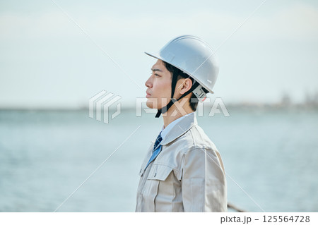 遠くを見つめる作業着姿の20代の若い男性 125564728