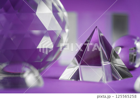 Crystal prism refracting light, magic crystals and pyramid, sphere and cube on purple background. Spiritual healing crystal practice. Feng Shui, good energy flow concept background.. Crystal prism refracting light, magic crystals and pyramid, sphere and cube on purple background. Spiritual healing crystal practice. Feng Shui, good energy flow concept background.. 125565258