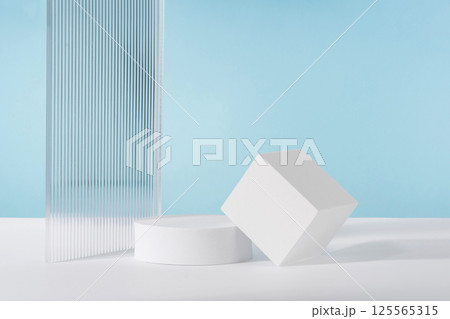 Acrylic ribbed plate, podium, background for cosmetic product packaging on blue backdrop. Showcase for jewellery presentation, display for perfume advertising, cosmetics branding scene 125565315
