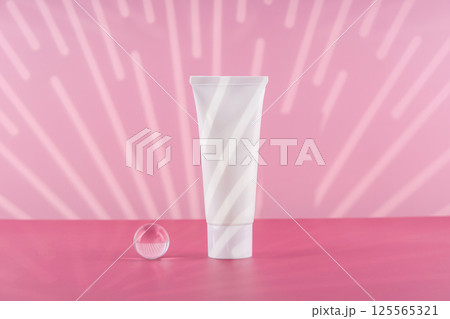 Unbranded cosmetic cream white plastic tube mockup on pink background with stylish props. Blank body and health care beauty product packaging. Moisturising hand creme bottle. 125565321