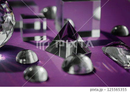 Crystal prism refracting light, magic crystals and pyramid, sphere and cube on purple background. Spiritual healing crystal practice. Feng Shui, good energy flow concept background.. Crystal prism refracting light, magic crystals and pyramid, sphere and cube on purple background. Spiritual healing crystal practice. Feng Shui, good energy flow concept background.. 125565355
