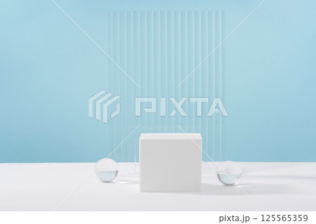 Acrylic plate, podium, background for cosmetic product packaging on blue backdrop with stylish props. Showcase for jewellery presentation, display for advertising, cosmetics branding scene 125565359