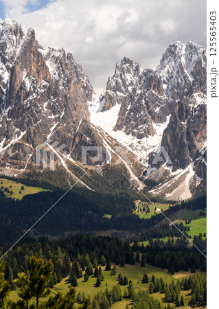 Majestic mountain landscape with snowy peaks and lush green valleys near Valley of Funes at Dolomites, Italy 125565403