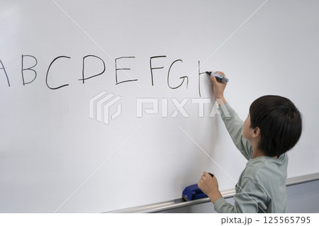 ホワイトボードにアルファベットを書く小学4年生の男の子 ホワイトボードにアルファベットを書く小学4年生の男の子 125565795
