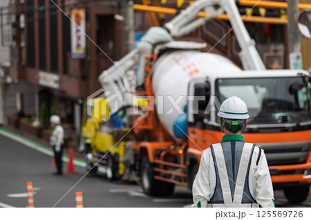 工事車両の停車する道路の交通を整理する交通誘導員 125569726