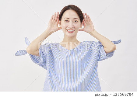 女性　ミドルエイジ　耳に手を当てて聞くジェスチャー　白背景 125569794