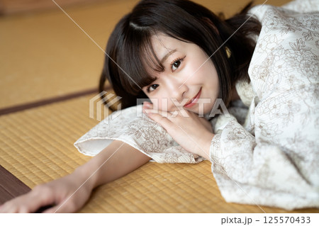 畳の部屋で休憩する浴衣の若い女性 125570433