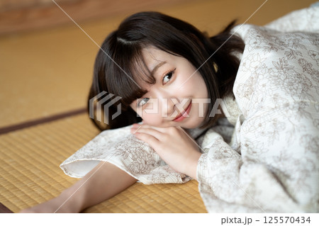 畳の部屋で休憩する浴衣の若い女性 125570434