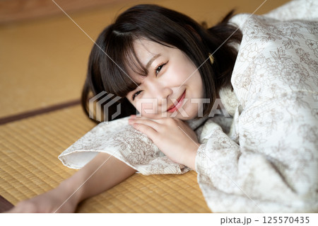 畳の部屋で休憩する浴衣の若い女性 畳の部屋で休憩する浴衣の若い女性 125570435