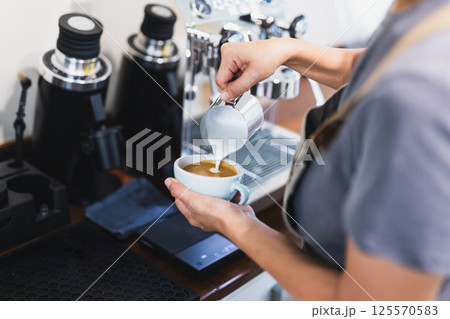 Woman barista pouring stream milk for making latte art. 125570583