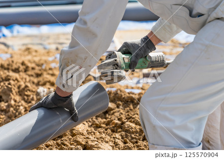 ディスクグラインダーで下水道配管のバリを取る土木作業員 ディスクグラインダーで下水道配管のバリを取る土木作業員 125570904
